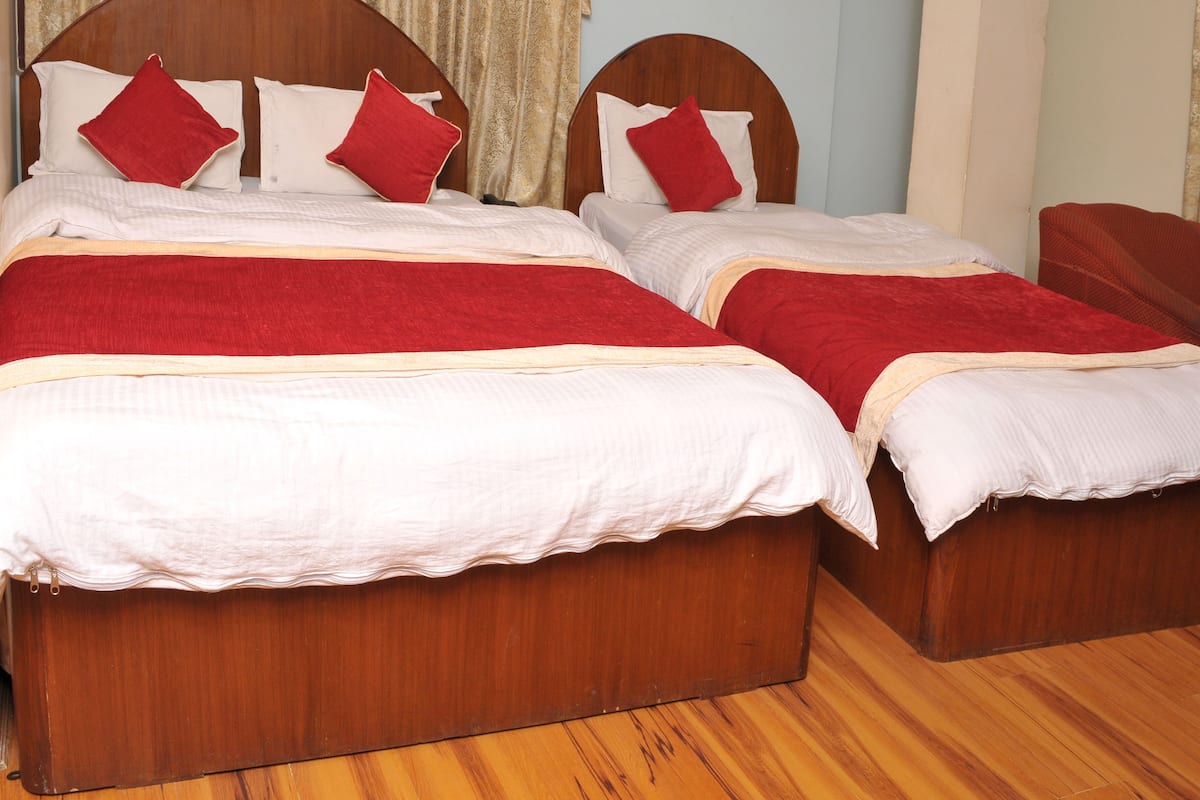 A double bed with a wooden headboard and red bedding.