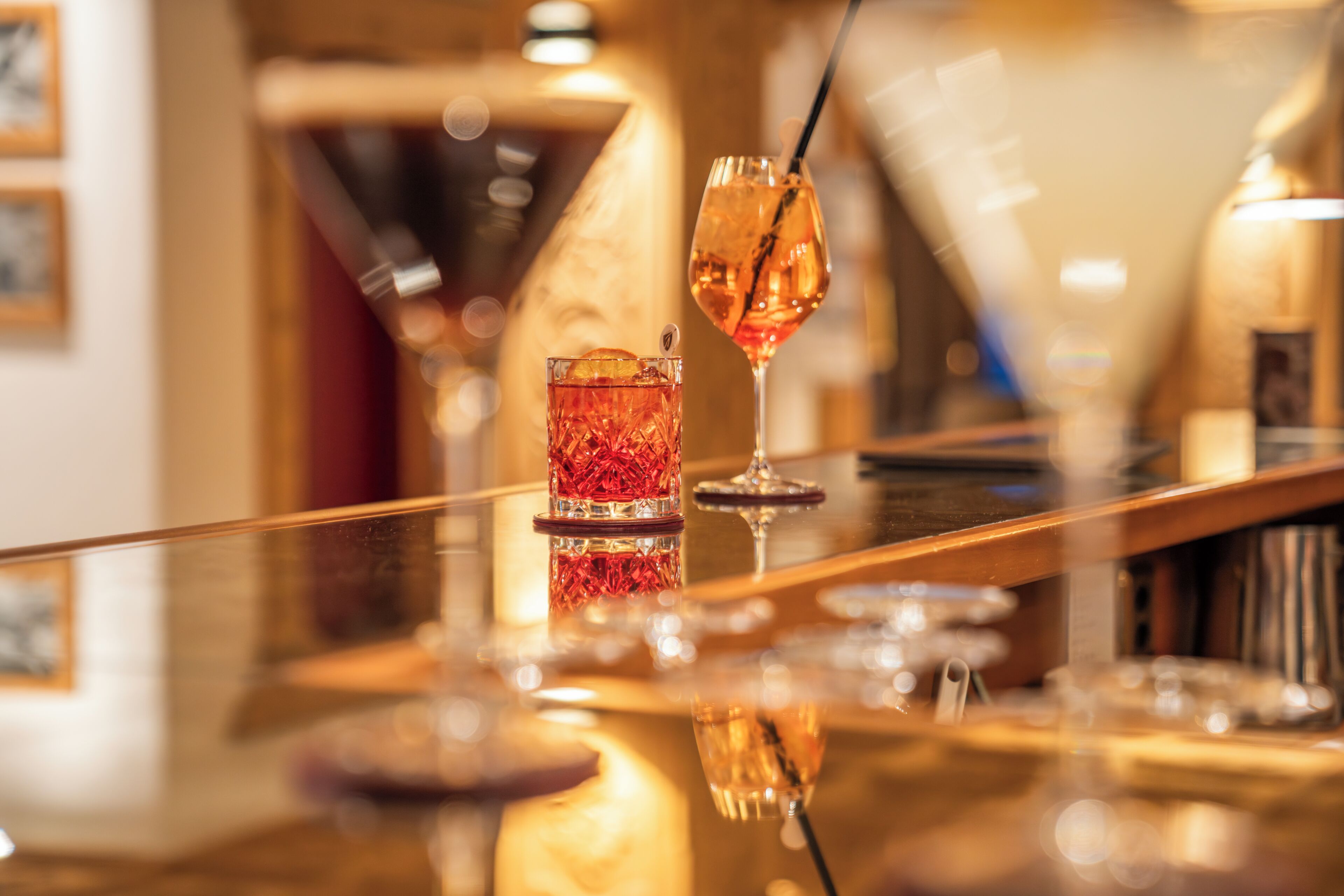 Un coin bar avec un verre de boisson rouge et un verre à vin muni d’une paille.