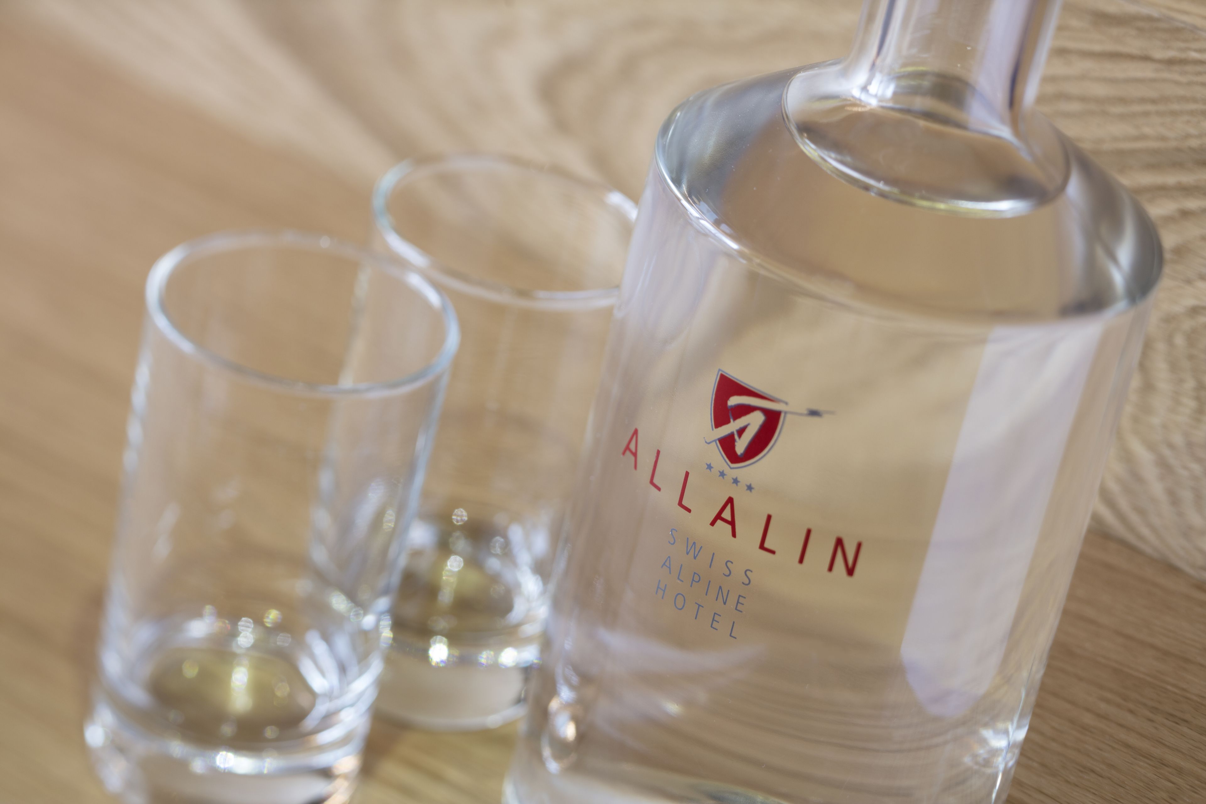 A bottle of Allalin Swiss Alpine Hotel liquor with two shot glasses.