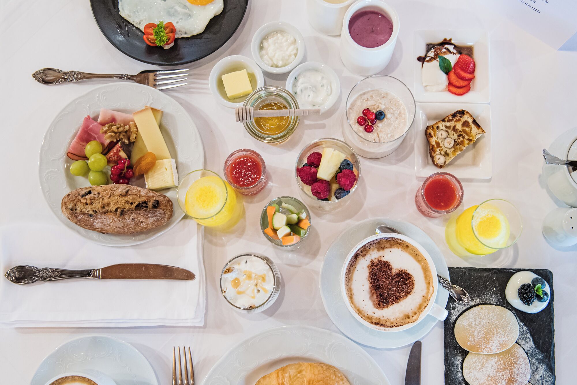 A breakfast buffet with various dishes, including eggs, pastries, and fruit.