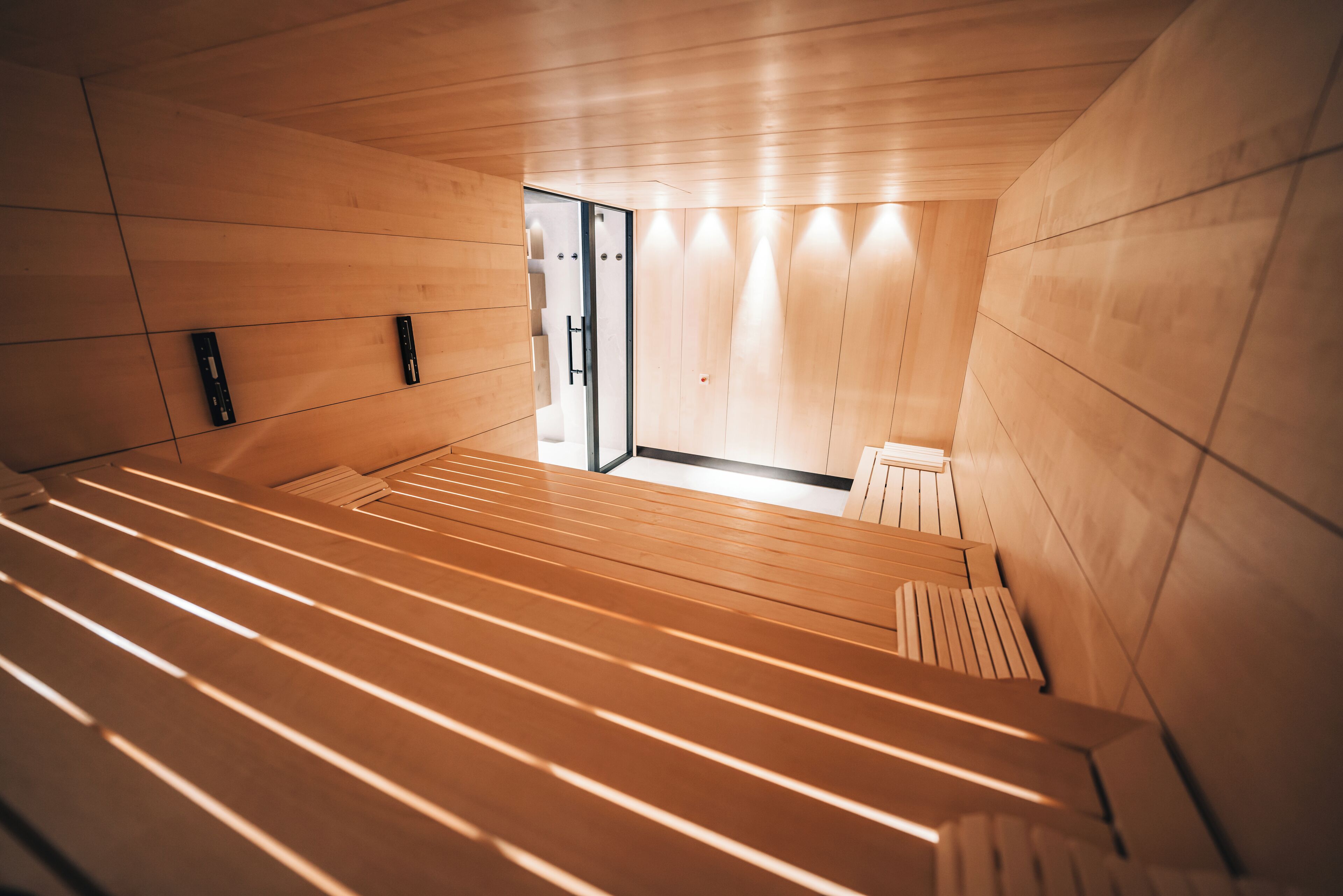 A modern, minimalist room with wooden paneling, a sloped ceiling, and a built-in bench.