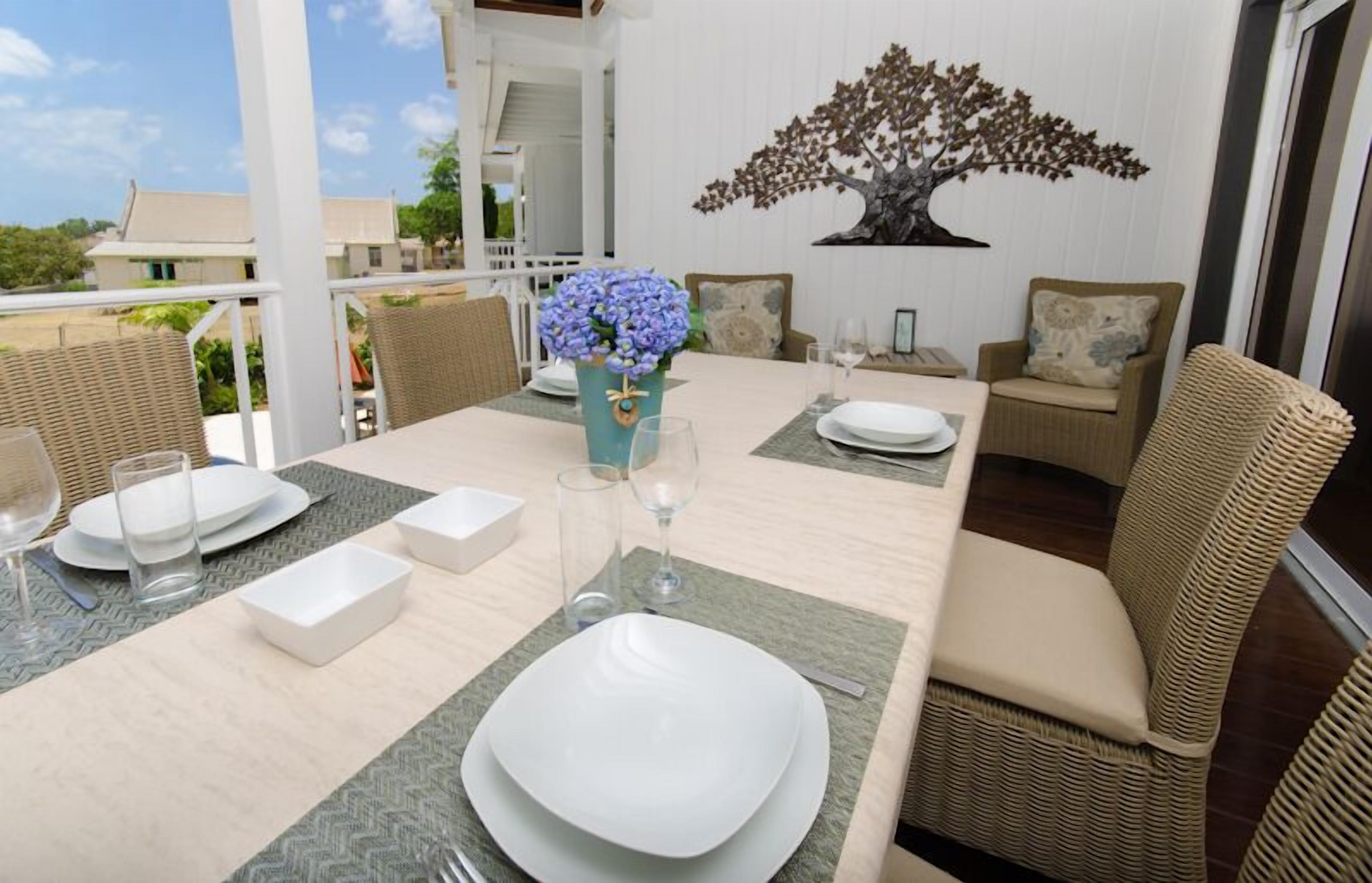 A dining area with a table set for four, including plates, glasses, and a vase with flowers.