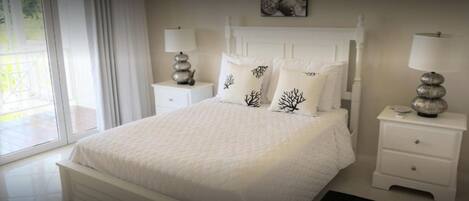 A neatly arranged bedroom with a large bed, two bedside tables with lamps, and a window providing natural light.