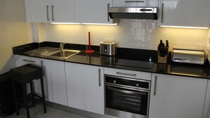 Una cocina moderna con armarios blancos, electrodomésticos de acero inoxidable y una encimera negra.