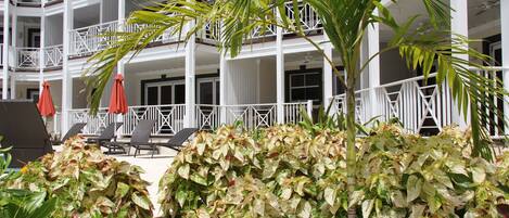 A multi-story hotel with balconies, outdoor seating, and lush greenery.