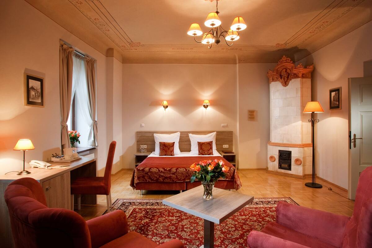 Una habitación de hotel con cama, escritorio, silla y una pequeña mesa con un florero.