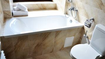 A bathroom with a bathtub, toilet, and a window.