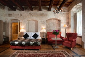 A room with a bed, two red armchairs, a small table with a vase, and a lamp. - Hotel Santi (Kraków)