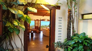 A doorway leading to a room with a view of the ocean, a stone wall with a decorative column, and a stone pathway. - Casa Rex by Sol Resorts (Vilanculos)