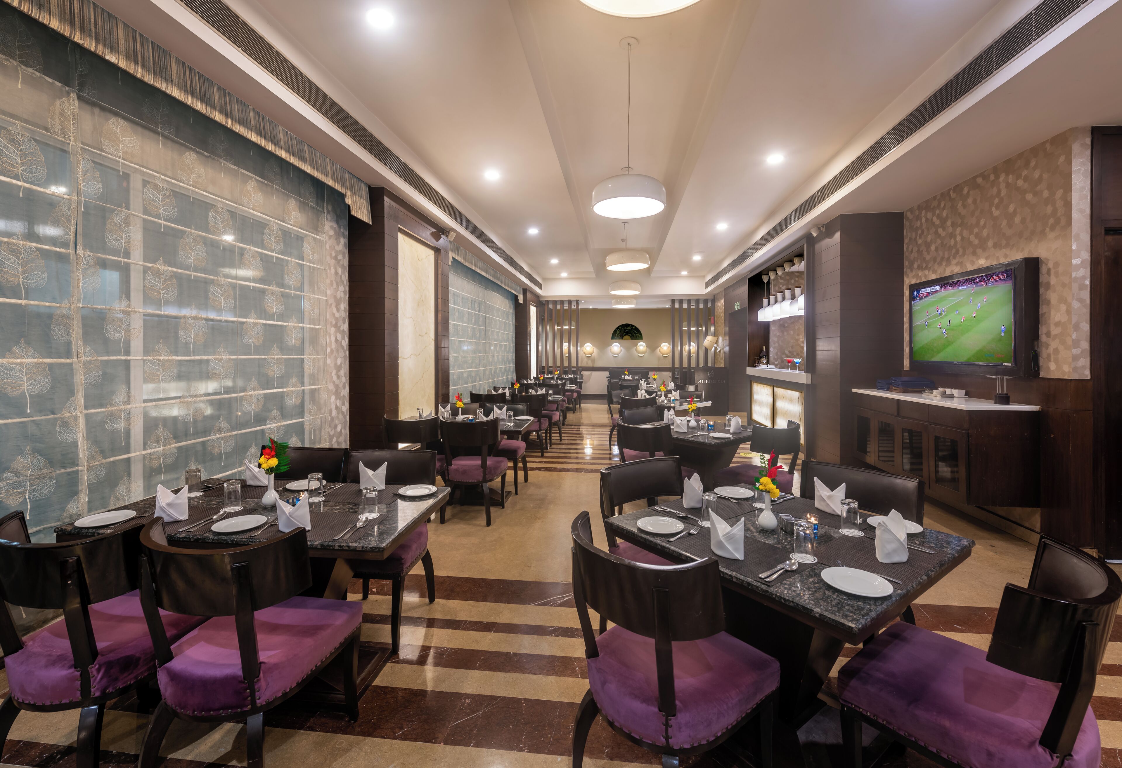 Un restaurante con varias mesas, sillas y una pantalla de televisión.
