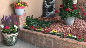 A landscaped garden with various potted plants and flowers, a decorative stone sculpture, and a brick border. - Red River Inn Silt-Rifle (Silt)