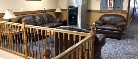 Un vestíbulo de hotel con sofás de cuero, un refrigerador y una escalera.
