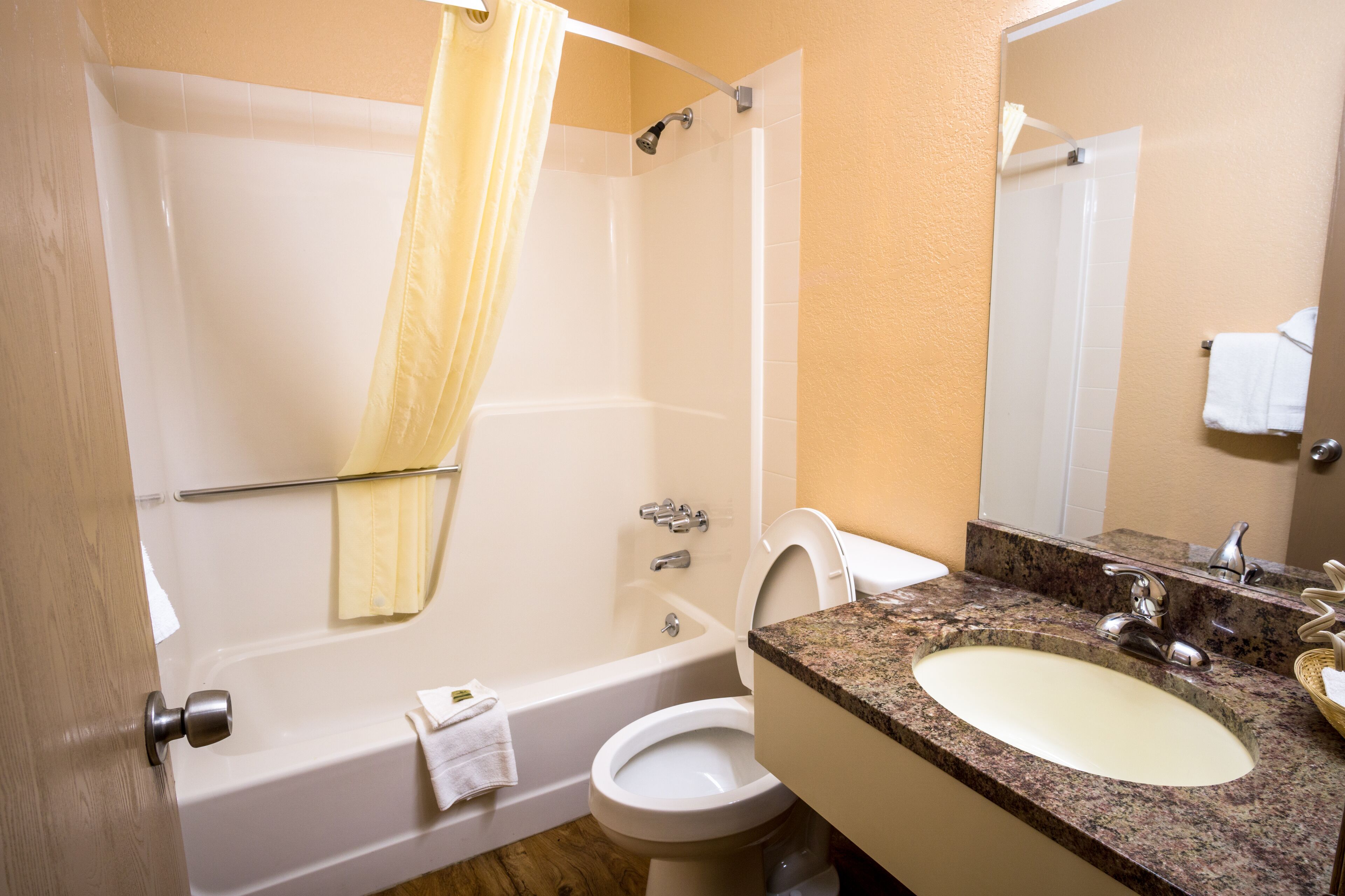 A bathroom with a bathtub, toilet, sink, and a mirror.
