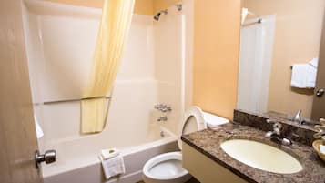 A bathroom with a bathtub, toilet, sink, and a mirror.