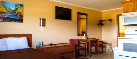 Habitación de hotel con dos camas, un escritorio, una silla, un televisor, microondas y un cuadro en la pared.