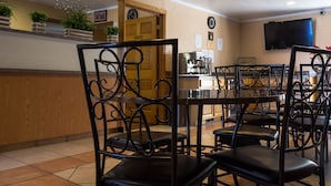 A restaurant with black metal chairs, a wooden counter, and a clock on the wall. - Red River Inn Silt-Rifle (Silt)