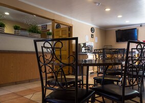 Um restaurante com cadeiras de metal preto, um balcão de madeira e um relógio na parede.
