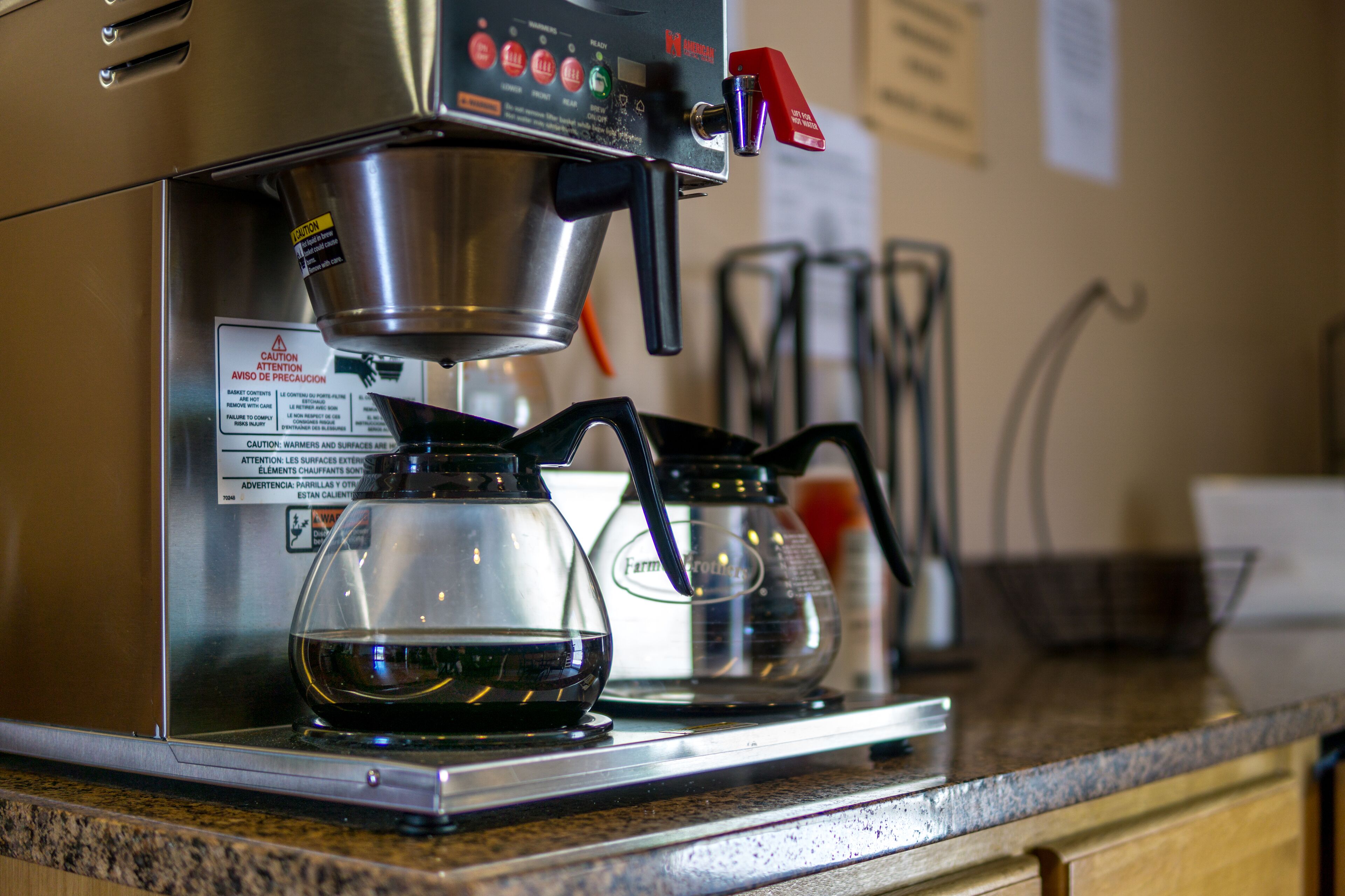 A coffee machine with a digital display and a red button, placed on a kitchen counter.