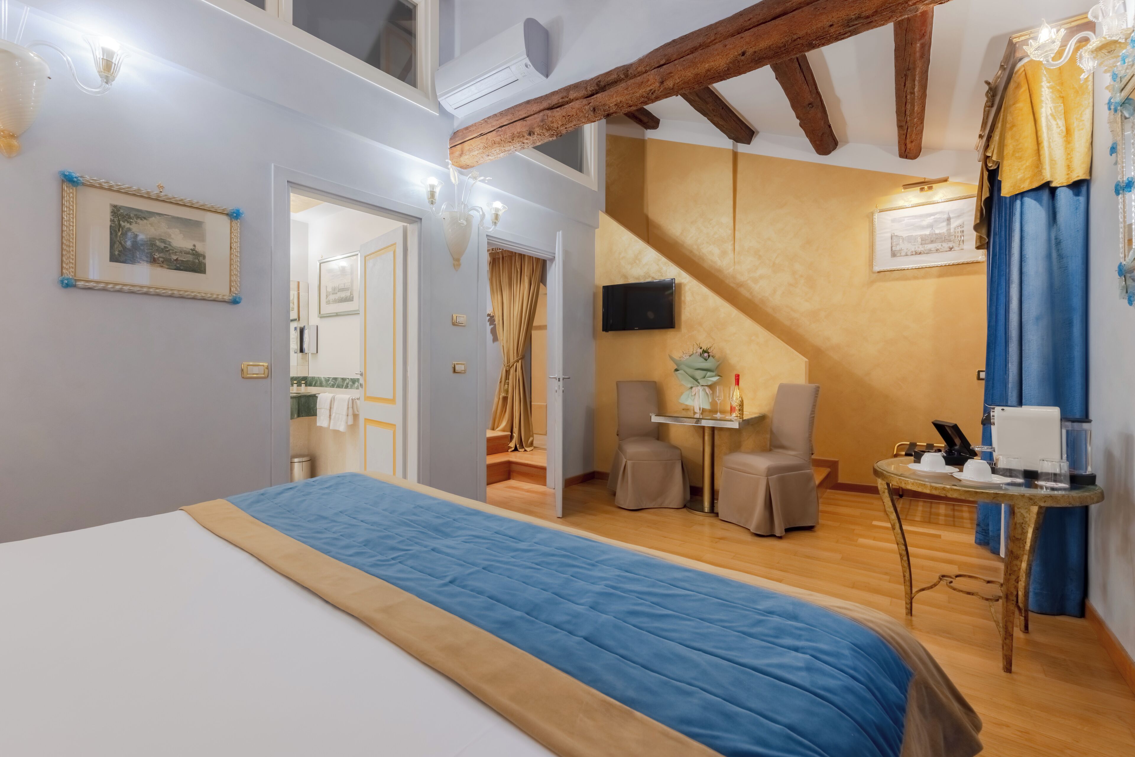 Une chambre d’hôtel avec un lit, une petite table avec une lampe, une chaise et un téléviseur fixé au mur.