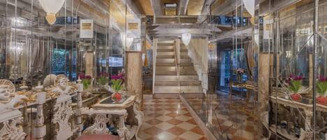 A hallway with ornate furniture, a checkered floor, and a staircase leading to another level.