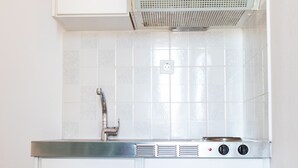 Una cucina compatta con frigorifero integrato, piano cottura e microonde.
