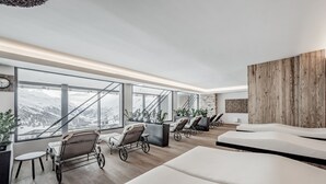 Un spa moderno con grandes ventanales, sillones reclinables y una pared de madera decorativa.