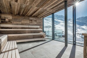 A modern interior with wooden paneling and a large glass window offering a mountain view. - SKI | GOLF | WELLNESS Hotel Riml (Soelden)