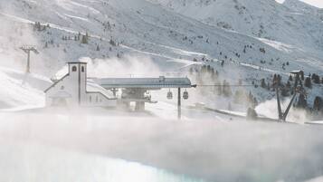 A snow-covered mountain with a ski lift and a building with a sign reading "HOCHGURGLBAHENEN".
