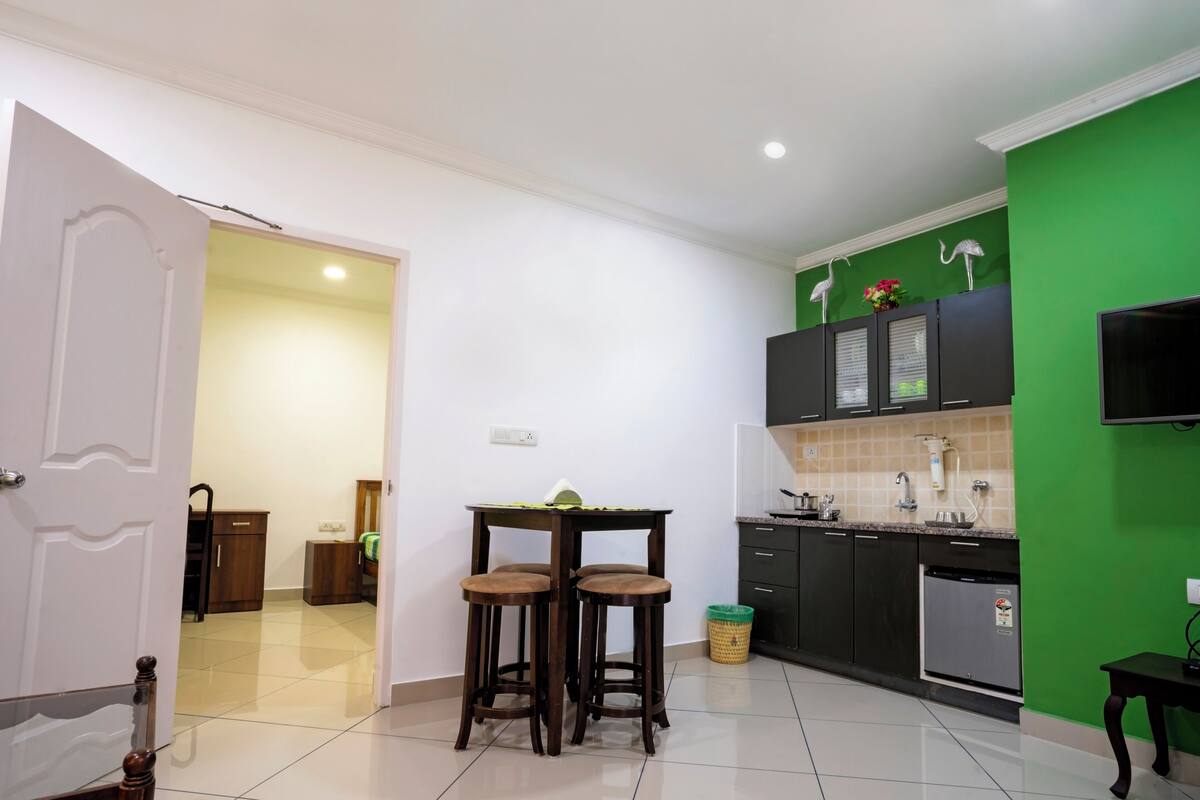 A kitchen with a green accent wall, a dining area with two stools, and a small table.