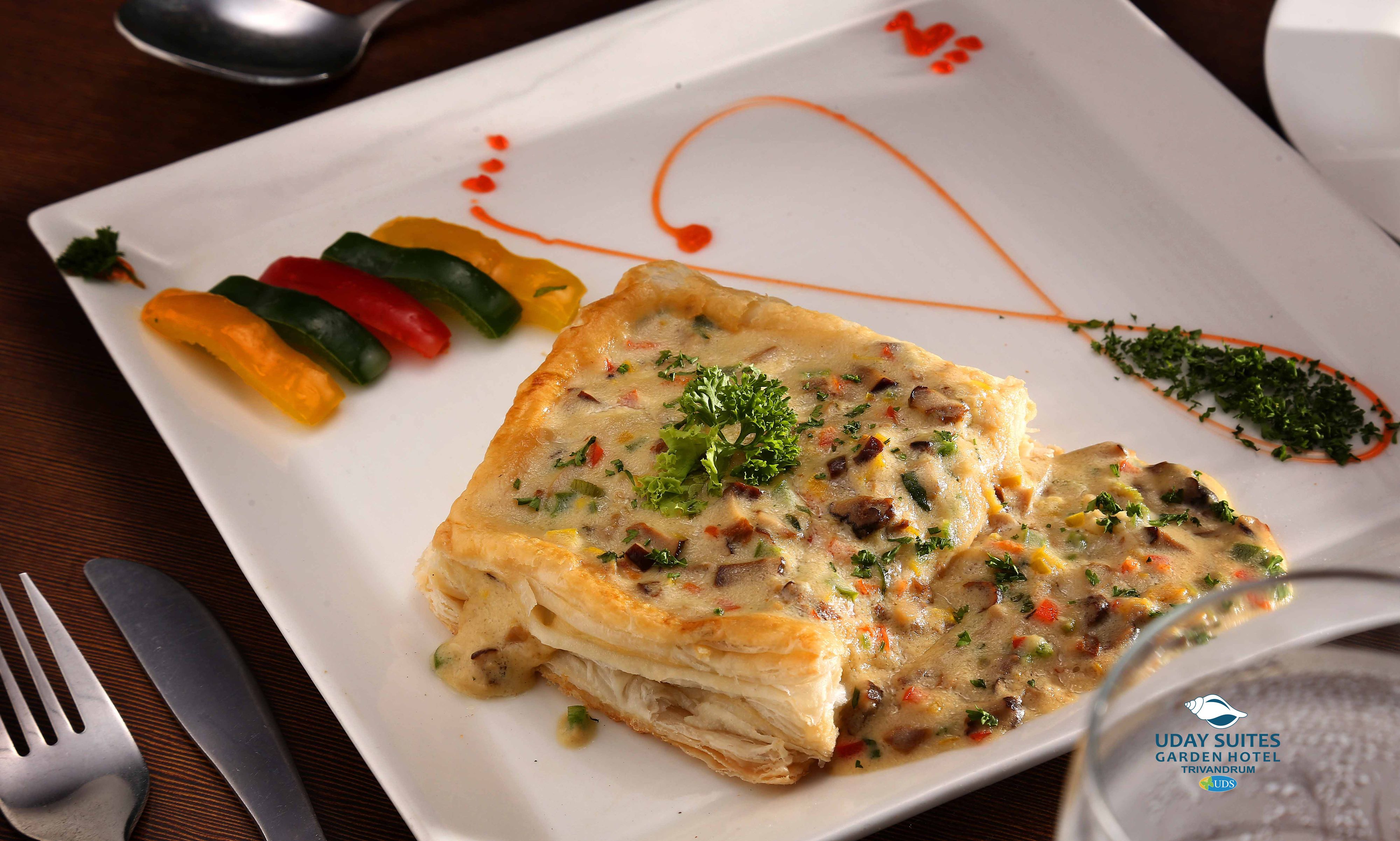 Un plato de comida con diversos vegetales y un guiso cremoso, posiblemente una cazuela, adornado con hierbas.