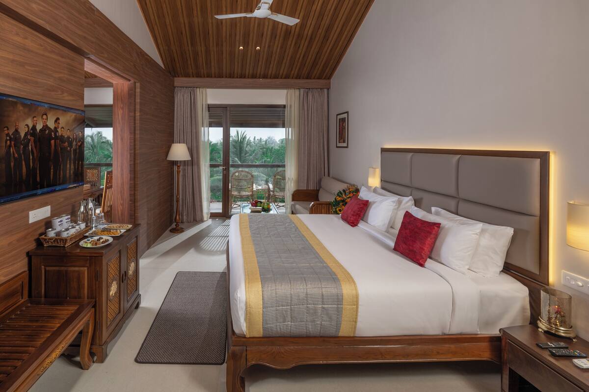 A spacious bedroom with a large bed, wooden headboard, and a balcony with a view.