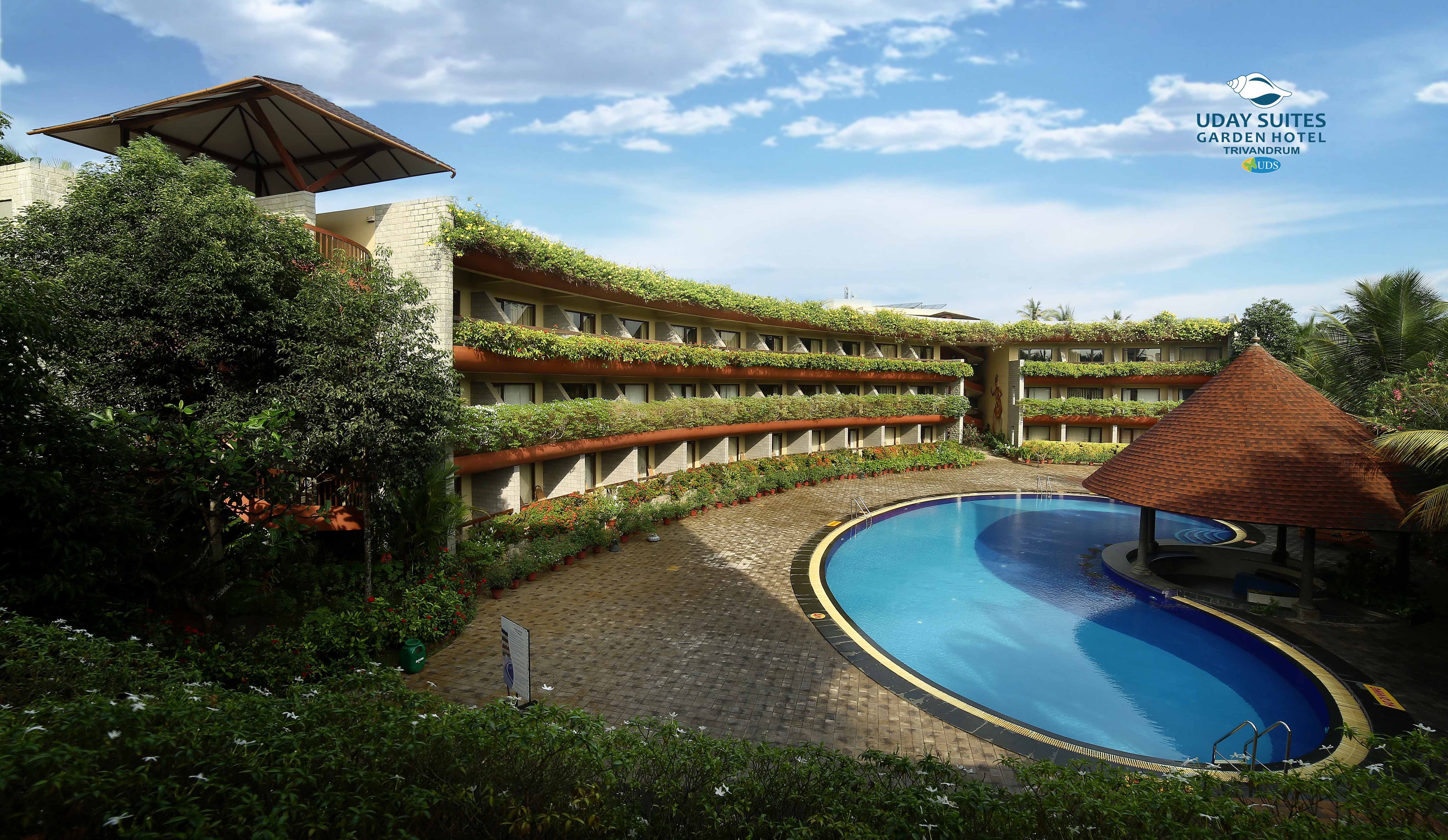 Un hotel con piscina, abundante vegetación y un diseño arquitectónico curvo distintivo.