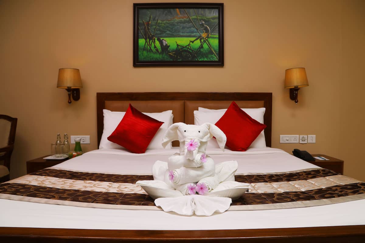 A neatly made bed with red pillows, a framed painting above, and two bedside lamps.