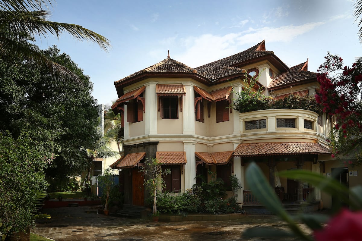 A large, multi-story building with a curved balcony and a tiled roof.