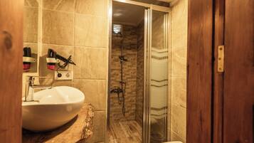 Un baño con lavamanos blanco, cabina de ducha de cristal y tocador de madera.