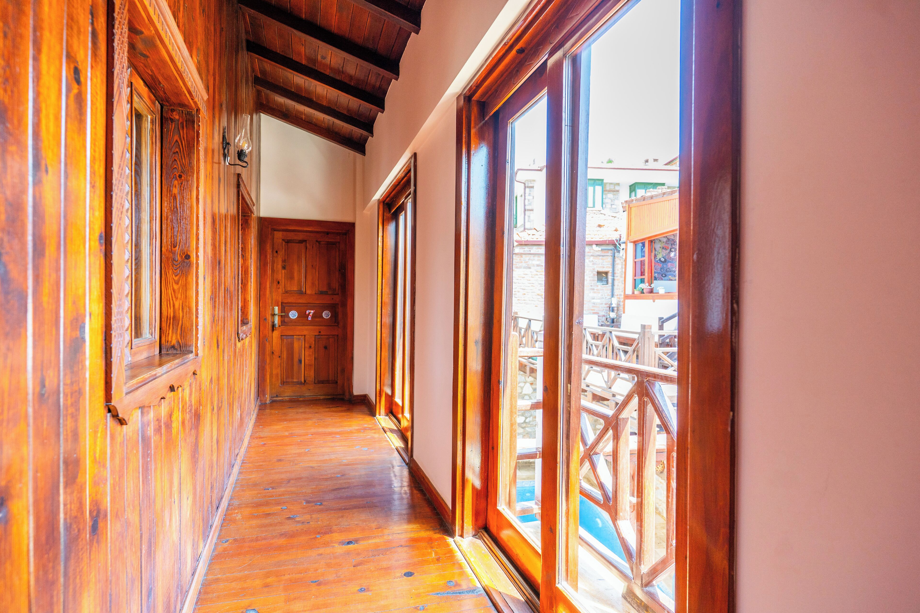 A wooden hallway with large windows and a view of outdoor seating.