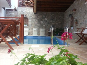 A stone-walled pool area with wooden deck chairs and a small pool. - Amazon Petite Palace (Selçuk)