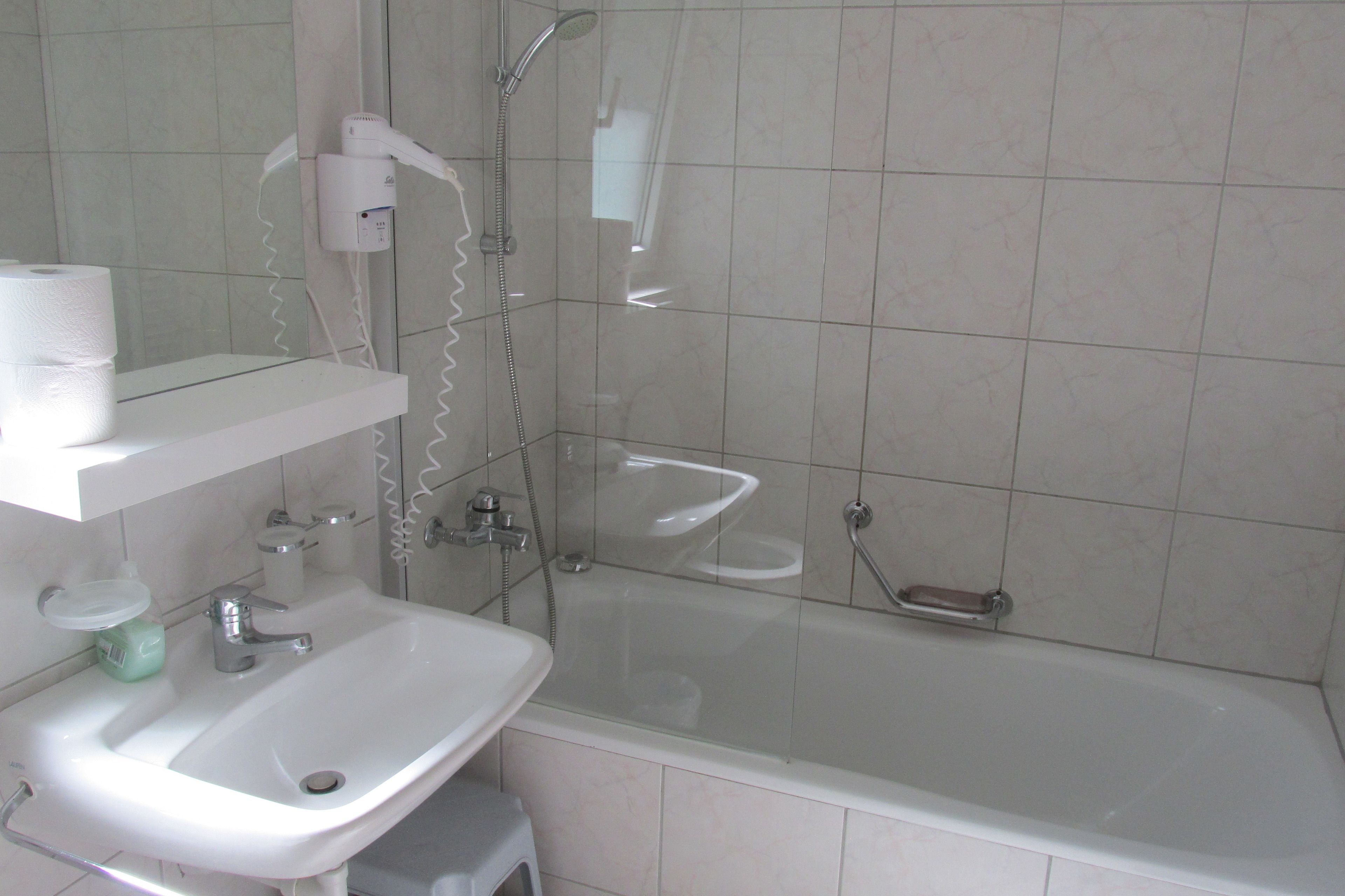A modern bathroom with a sink, mirror, and glass-enclosed shower.