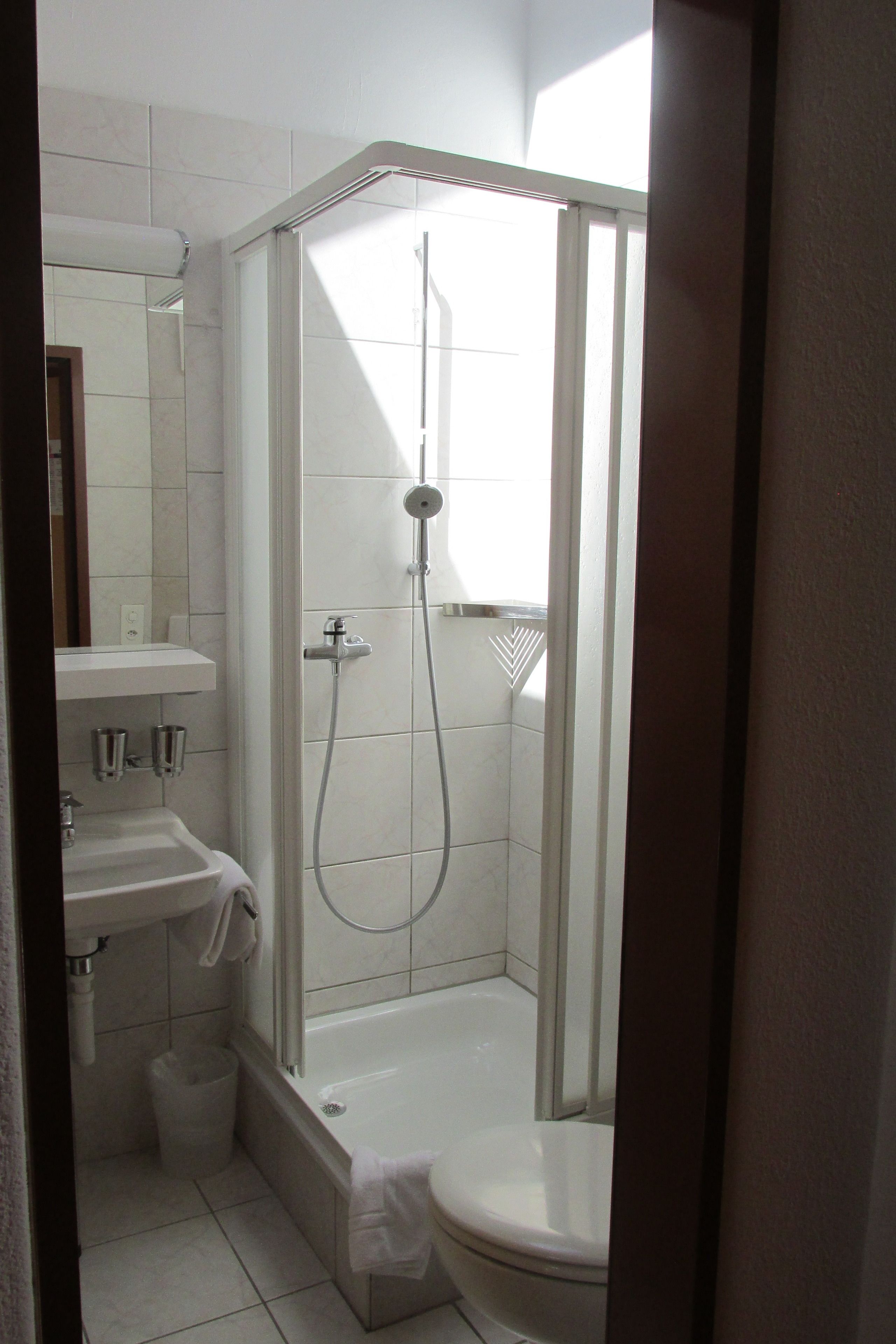 A bathroom with a shower, toilet, sink, and mirror.