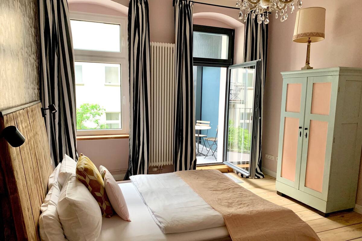 A bedroom with a bed, a nightstand, a dresser, and a view of the outside balcony.