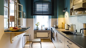 Una cocina con encimera de madera, un fregadero, una estufa y una ventana con persianas.