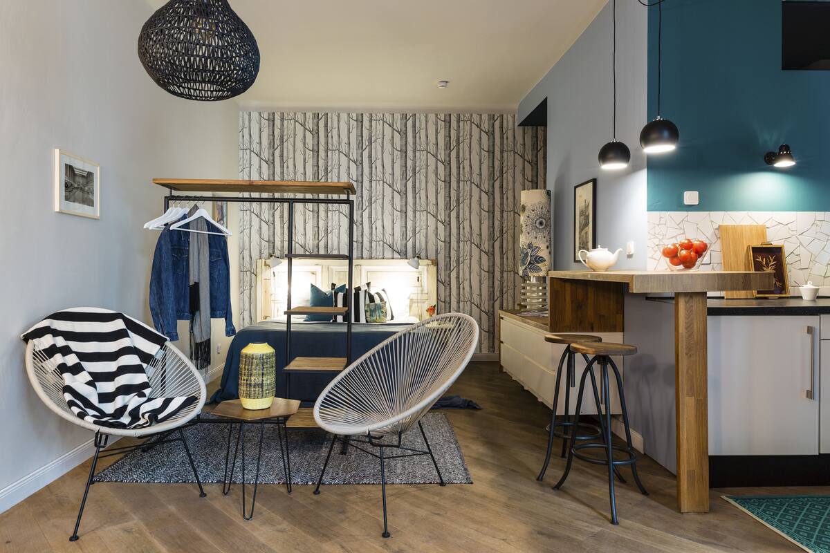 A modern kitchen with a wooden island, bar stools, and a hanging light fixture.