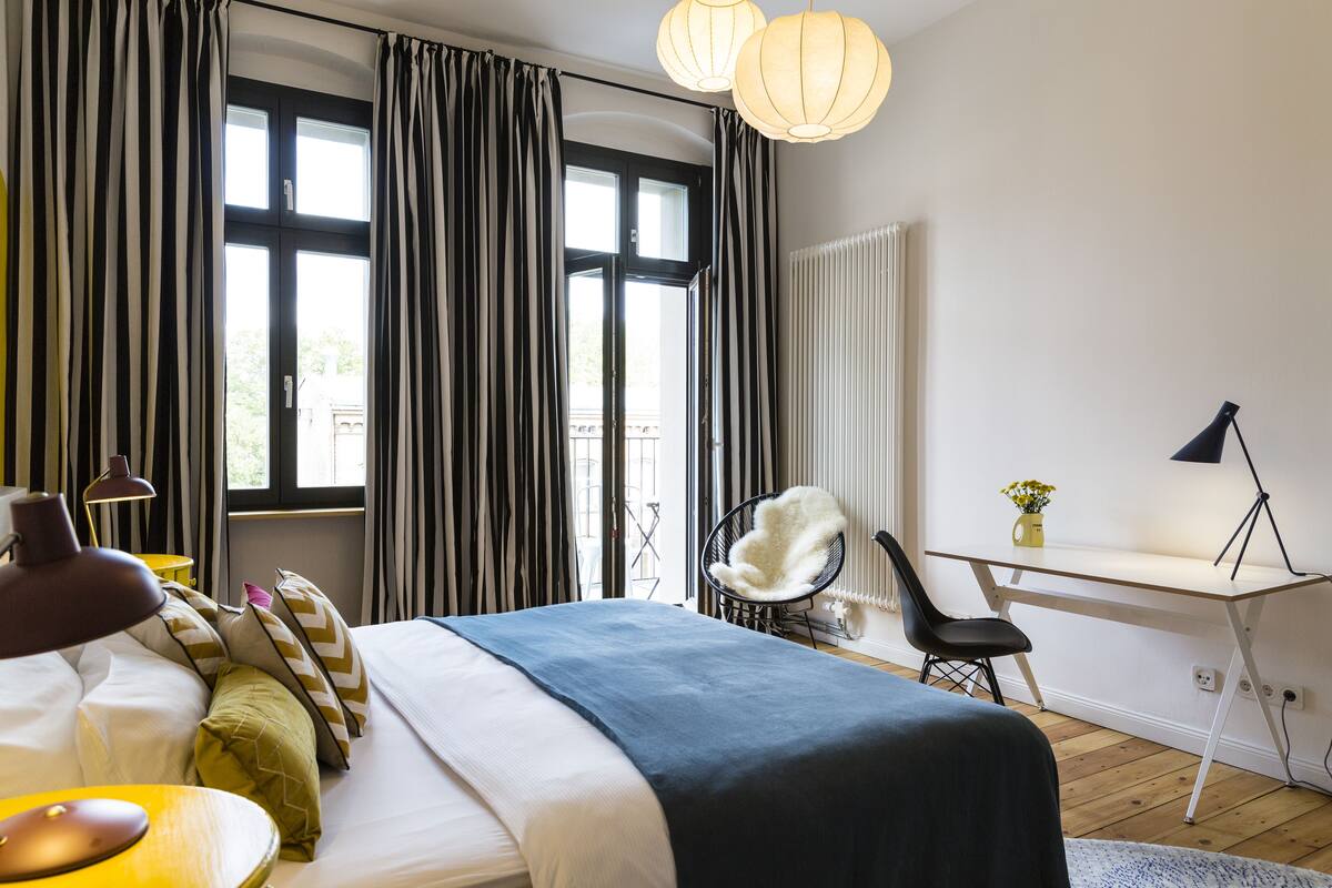 A modern bedroom with a large bed, a desk, and a chair.