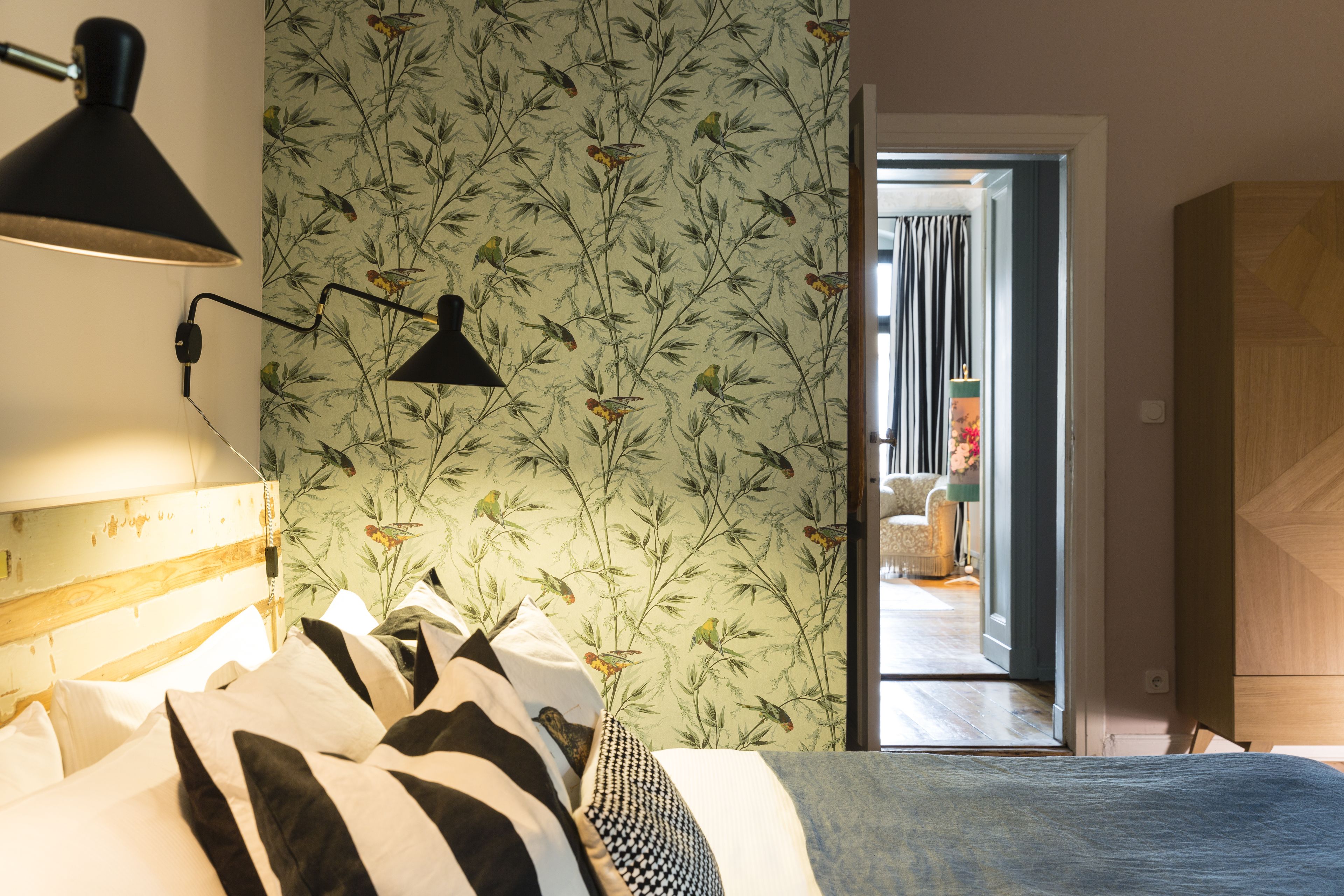 Une chambre à coucher avec un lit, une lampe et un papier peint à motifs floraux.