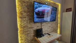 A flat-screen TV mounted on a brick wall with a wooden table in front. - Rainbow Apartments 2 (Kraków)