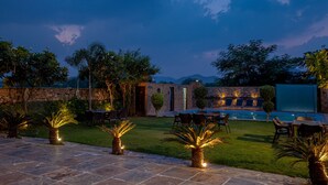 An outdoor patio area with stone flooring, seating arrangements, and a swimming pool. - Zone Connect by The Park Udaipur (Udaipur)