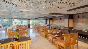 A spacious dining area with wooden tables and chairs, a patterned ceiling, and a view of the outdoors. - Zone Connect by The Park Udaipur (Udaipur)