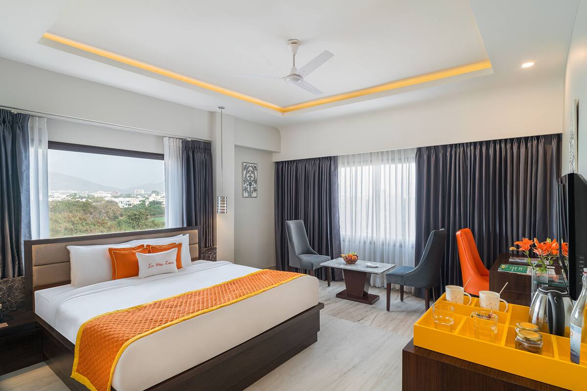 A hotel room with a large bed, a desk with a coffee maker, and a view of the city.