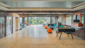 A spacious lobby with a foosball table, seating area, and a view of greenery outside. - Zone Connect by The Park Udaipur (Udaipur)