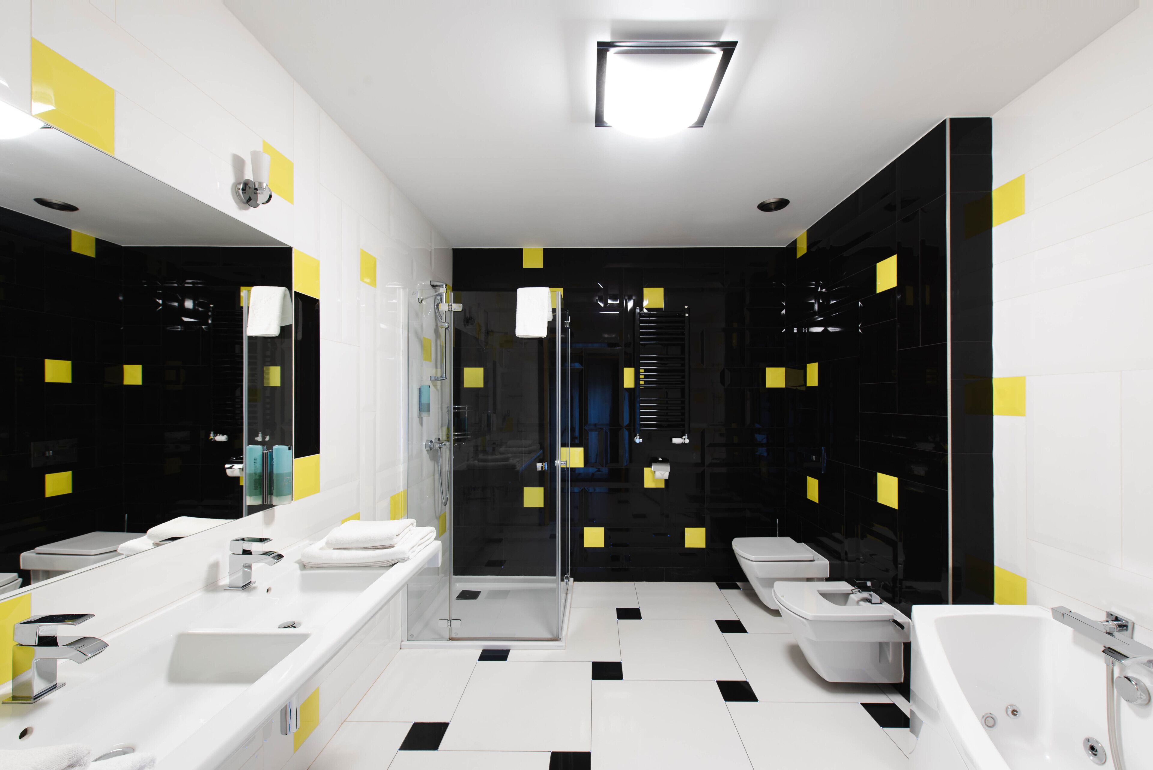 A modern bathroom with a large mirror, two sinks, a toilet, and a bathtub.